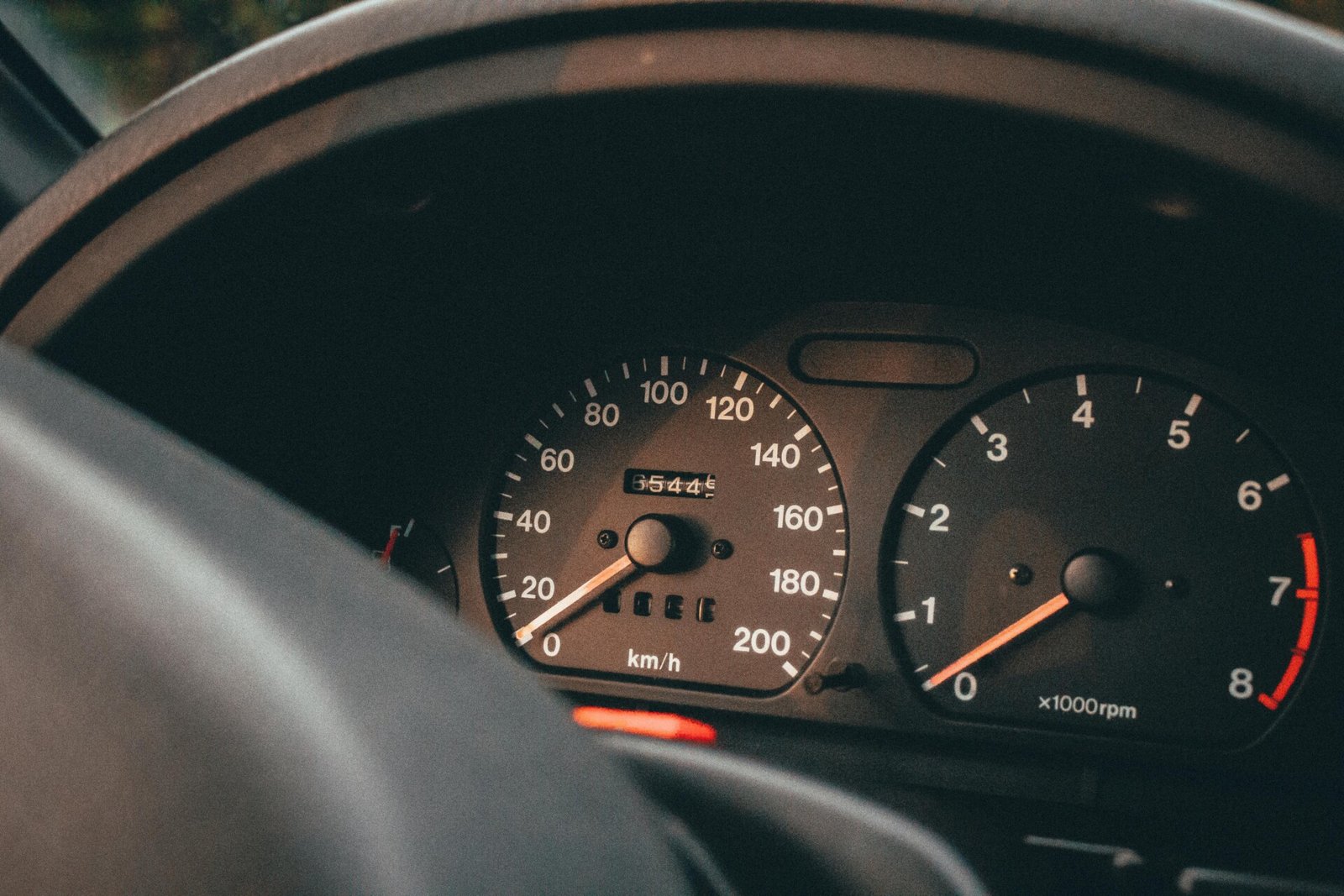Um close-up do painel de um carro revela a verdade sobre seu quilometragem dos veículos: o velocímetro marca zero quilômetros por hora, enquanto o odômetro marca 55.464 quilômetros. À direita, o tacômetro mede revoluções por minuto. | Velocidade5.cv